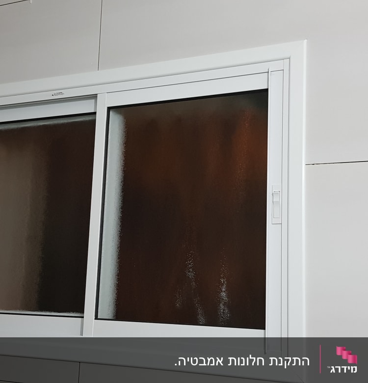 חלון אלומיניום עם מסגרת לבנה על קיר